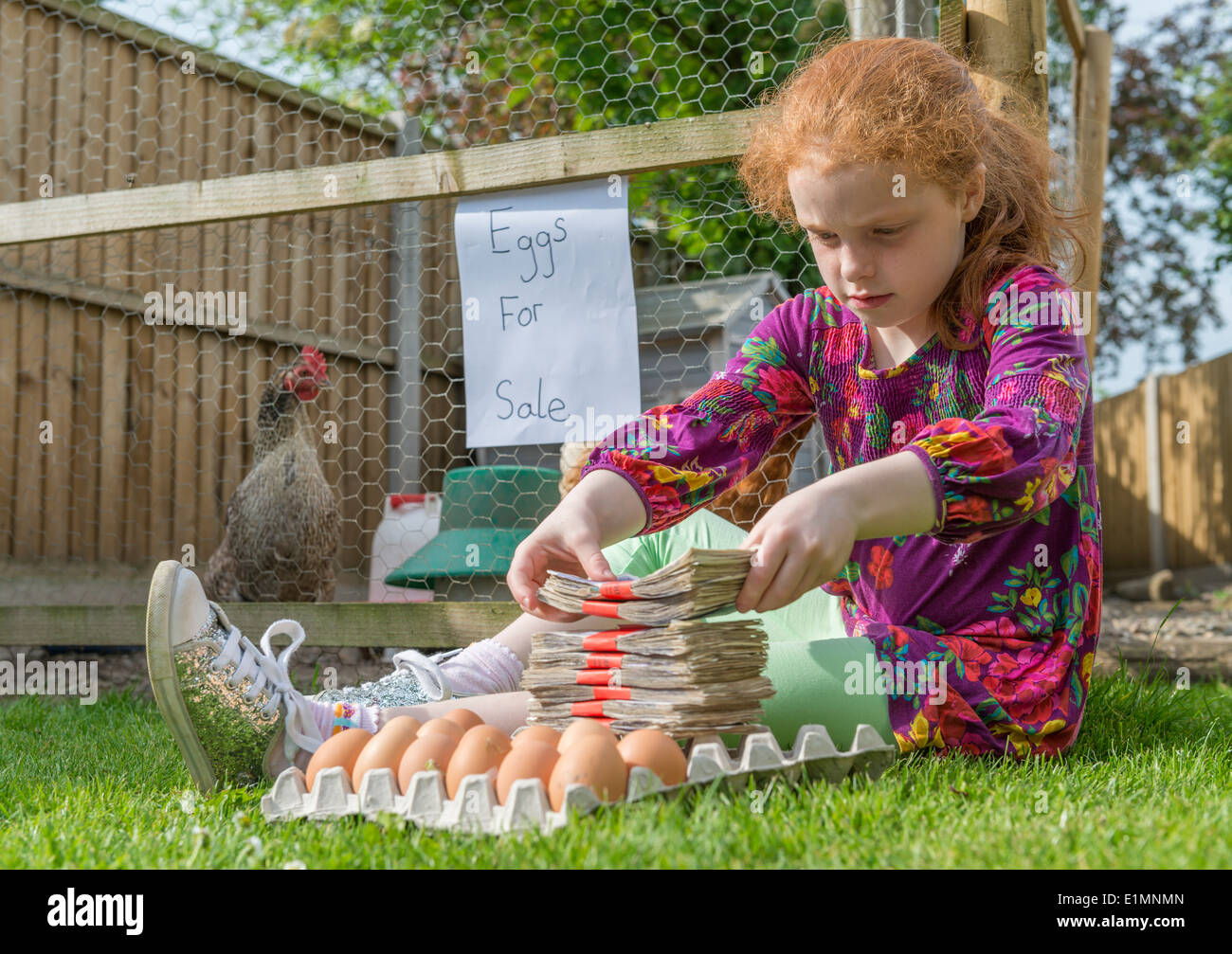 Petite fille entrepreneur siège avec des milliers de livres, tout en vendant des oeufs de poules. Banque D'Images