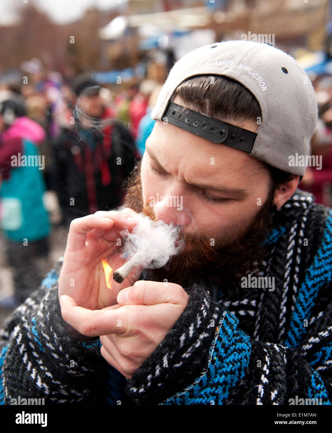 Un homme allume une cigarette de marijuana, ou joint, au cours d'une célébration du jour de 420 dans le village de Whistler. Whistler, BC, Canada. Banque D'Images