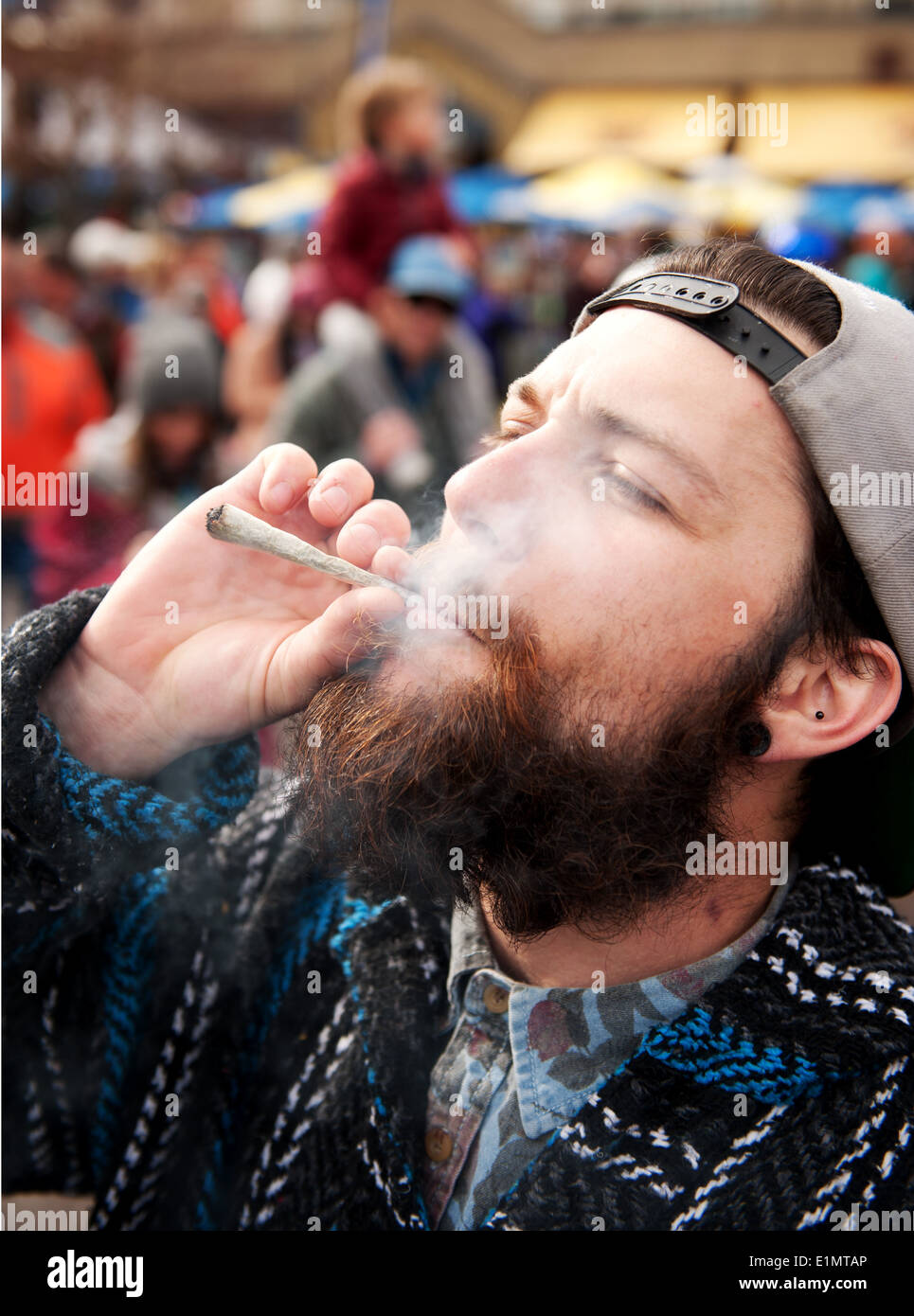Un homme allume une cigarette de marijuana, ou joint, au cours d'une célébration du jour de 420 dans le village de Whistler. Whistler, BC, Canada. Banque D'Images