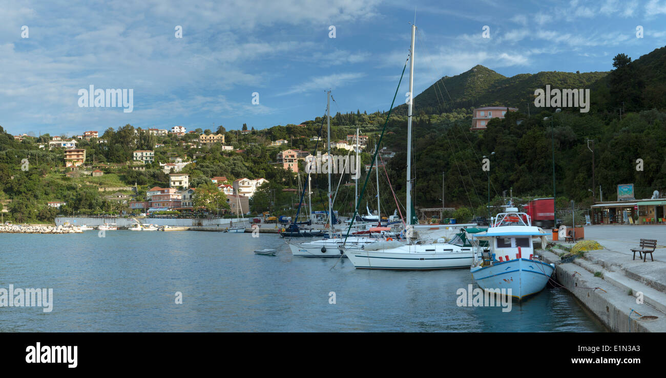 Les bateaux de pêche et yachts amarrés au port de Poros, Céphalonie, comme les dernières lueurs du jour brille sur les maisons sur la colline. Banque D'Images