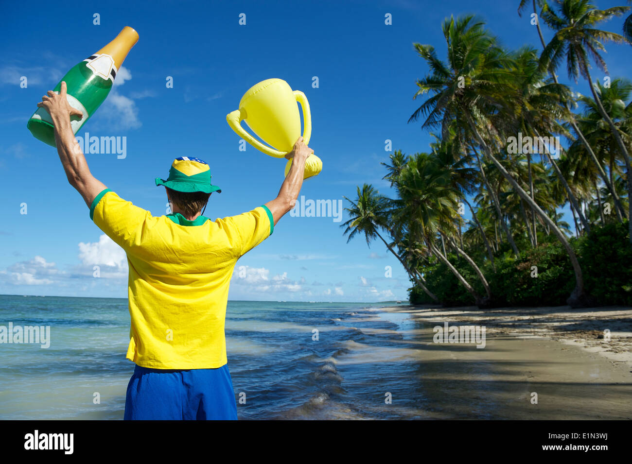 Joueur de football brésilien, l'équipe de couleurs Brésil holding trophy et la célébration de Champagne sur la plage, dans le Nordeste Bahia Banque D'Images