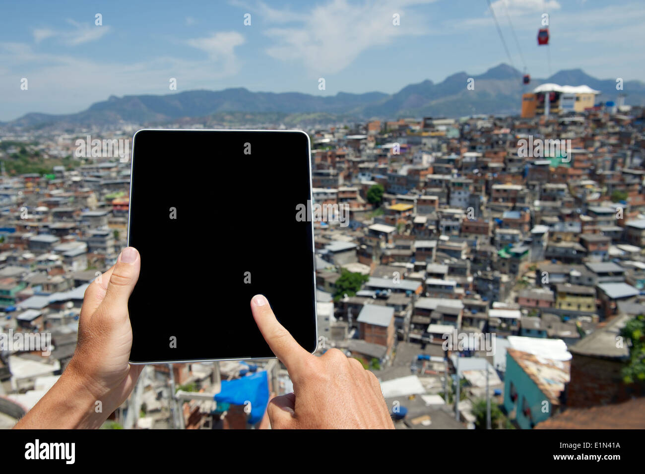 Mains à l'aide d'ordinateur tablette numérique vierge en face de bidonville brésilien favela Complexo do Alemao à Rio de Janeiro Brésil Banque D'Images