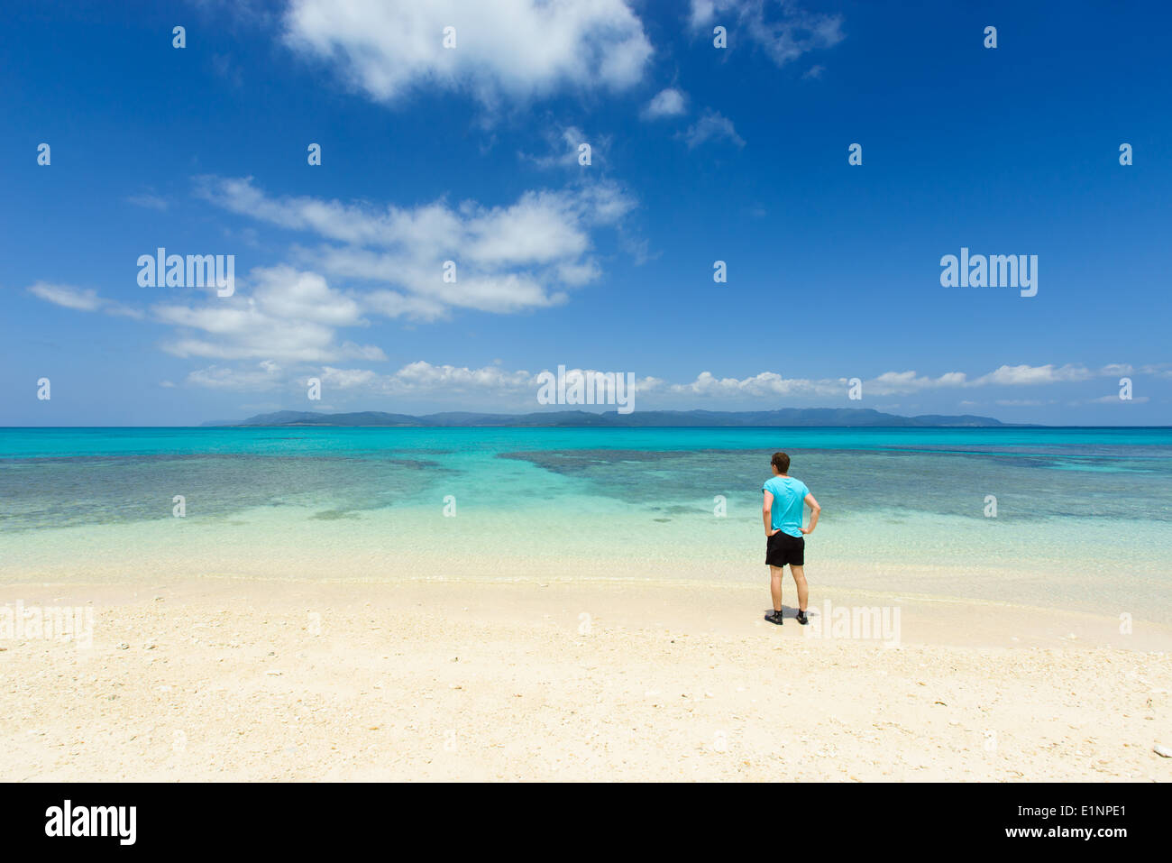 L'homme parfait admiratifs plage de sable blanc entourée d'eau tropicale d'Okinawa, Japon Banque D'Images