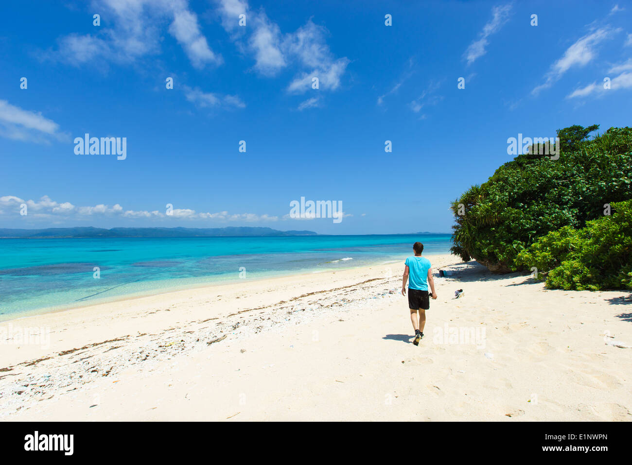 L'homme marchant sur une plage de sable blanc entourée par des eaux tropicales des îles Yaeyama, Okinawa, Japon Banque D'Images