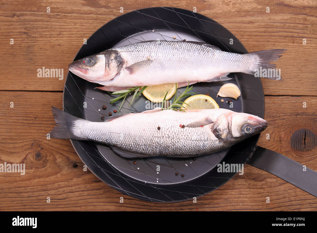 Deux nouvelles moronidae poisson sur poêle avec ingrédients, vue d'en haut Banque D'Images