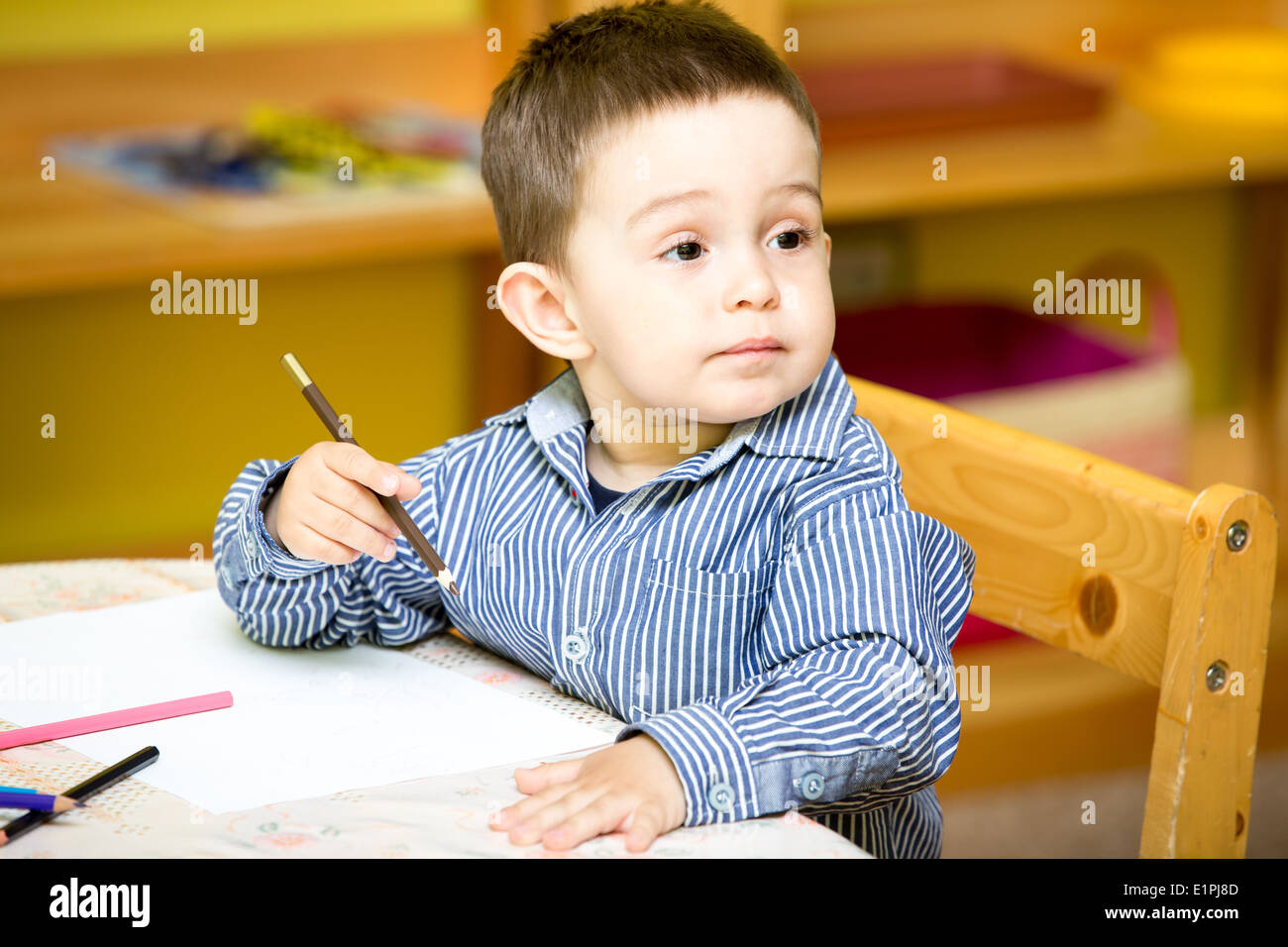 Petit enfant garçon dessin avec des crayons de couleurs dans l'enseignement préscolaire à la table dans le jardin d'enfants Banque D'Images