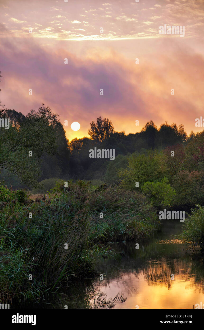 Lever du soleil sur la rivière avec de beaux nuages d'or en été Banque D'Images