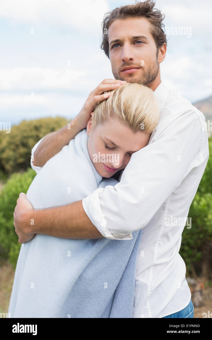 L'homme protecteur hugging son amie en couverture bleue à l'extérieur Banque D'Images