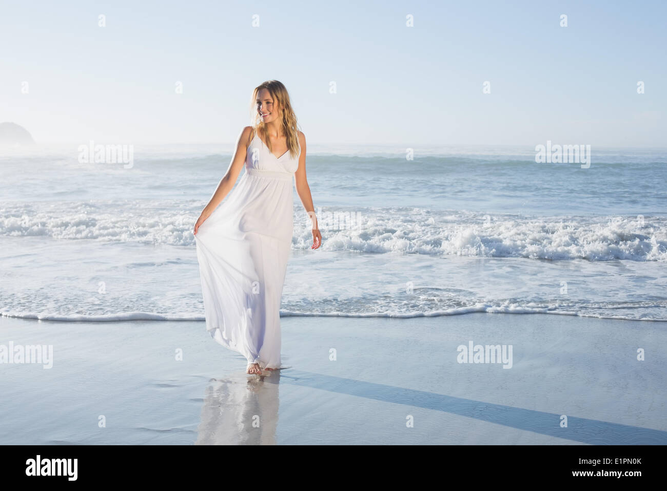 Belle blonde à la plage en robe blanche Banque D'Images