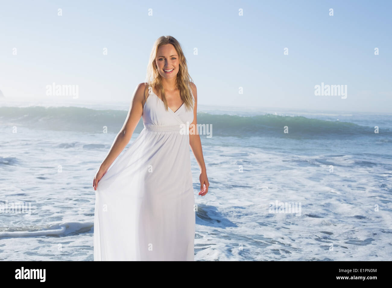 Belle blonde à la plage en robe blanche Banque D'Images
