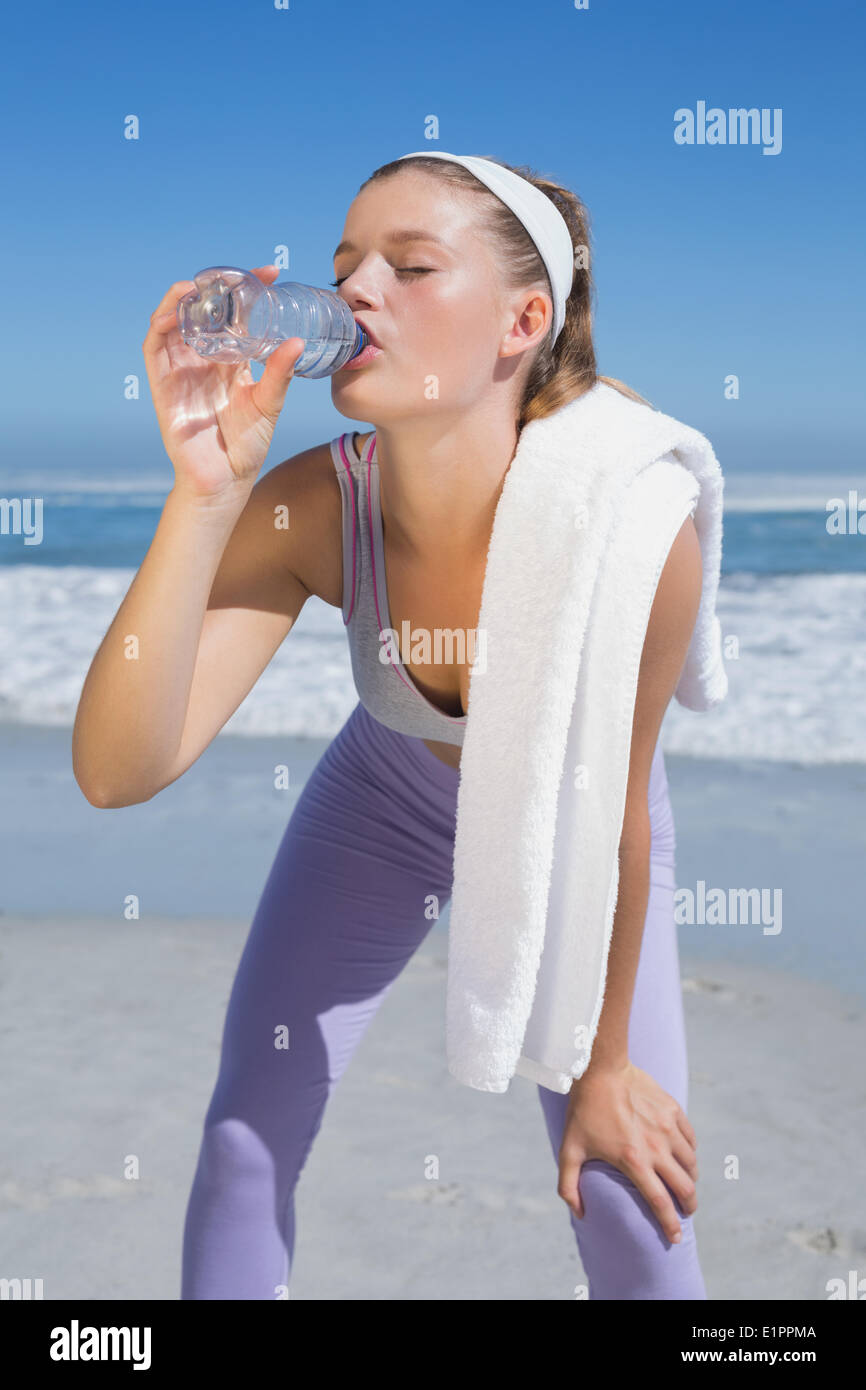 Assez sportive blonde l'eau potable sur la plage Banque D'Images