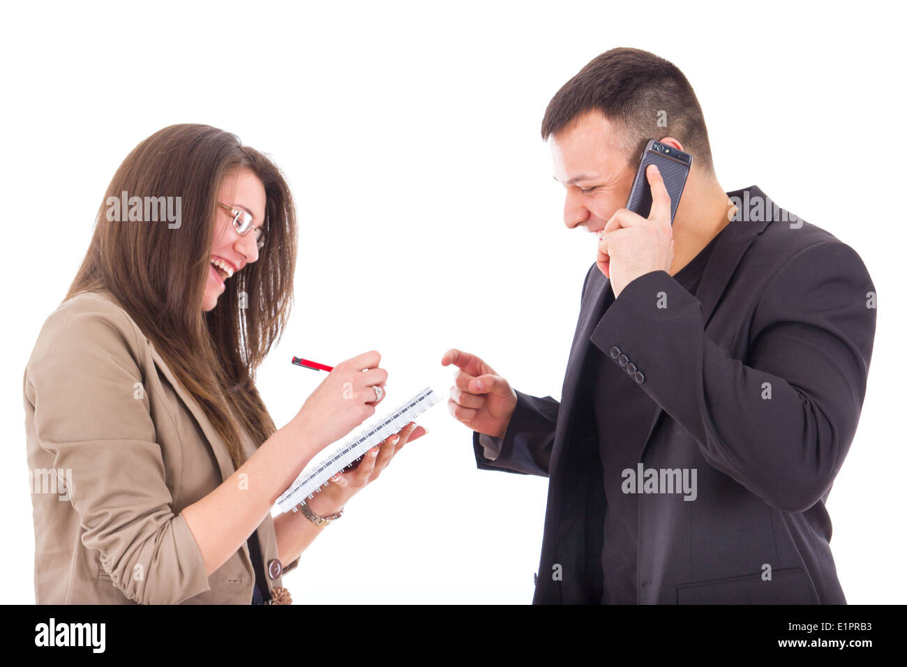 Smiling businessman sur le téléphone et sa secrétaire écrit des notes Banque D'Images Smiling businessman sur le téléphone et sa secrétaire écrit des notes Banque D'Images