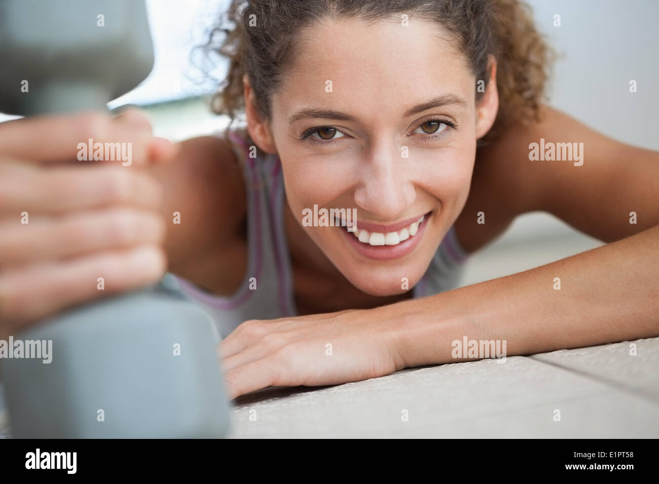 Fit woman smiling at camera holding dumbbell Banque D'Images