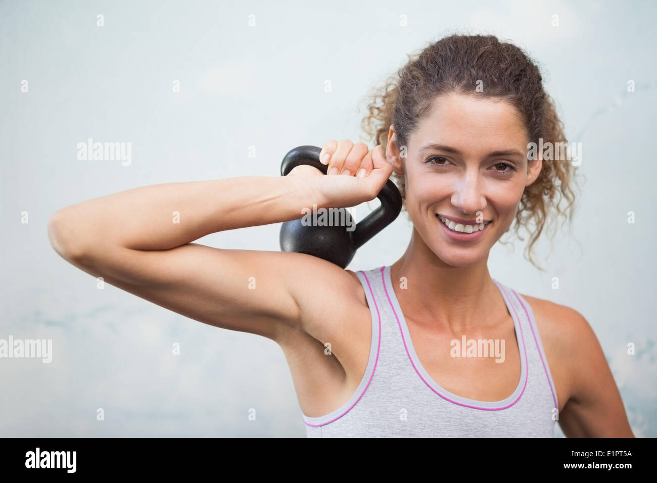 Fit woman smiling at camera holding kettlebell Banque D'Images