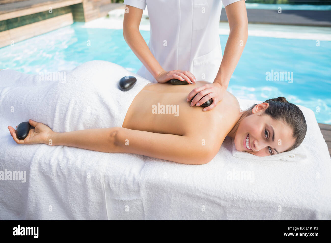 Heureux brune s un massage aux pierres chaudes piscine Banque D'Images