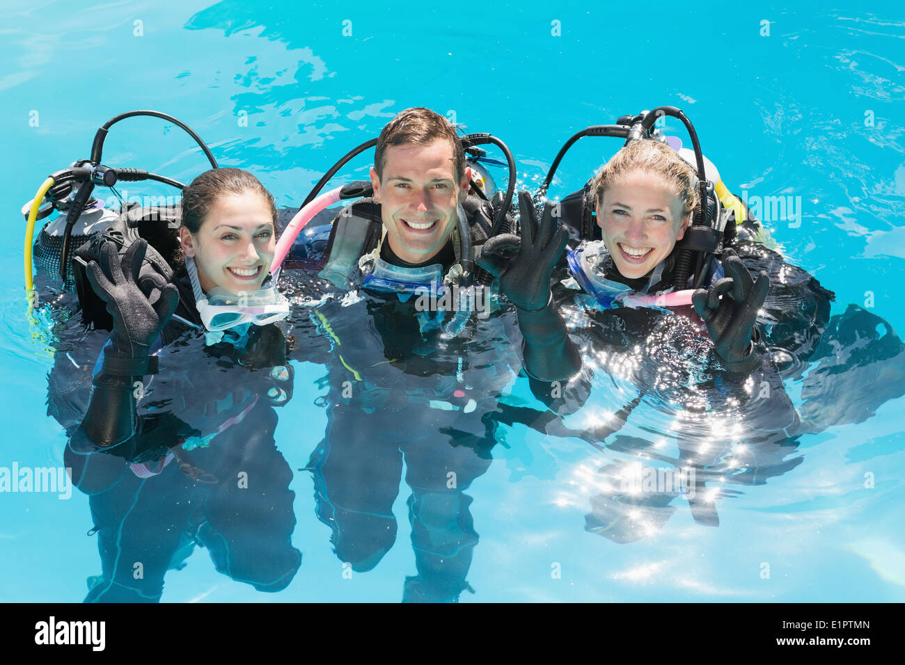 Smiling friends sur scuba training in swimming pool looking at camera Banque D'Images