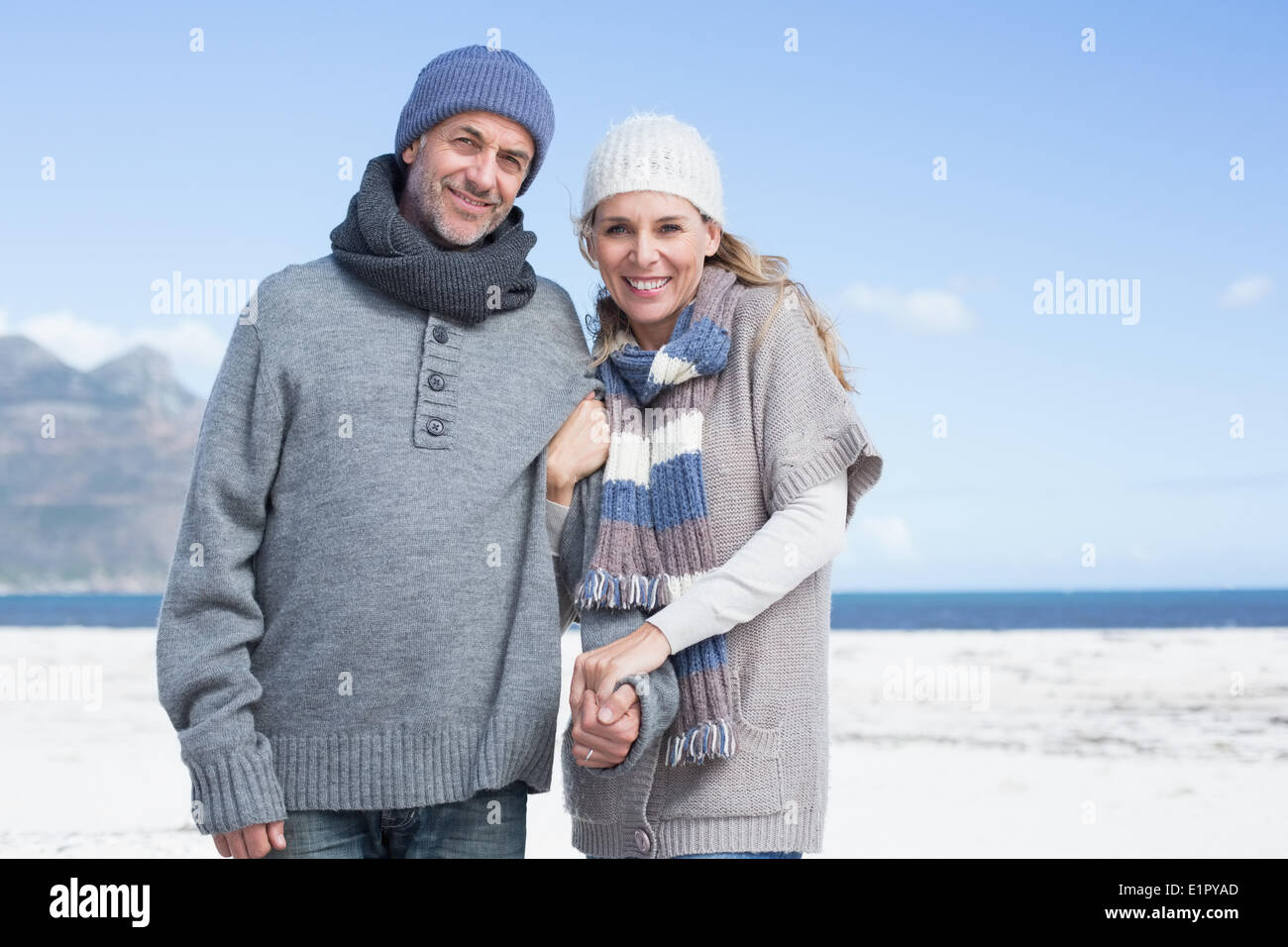 Smiling couple debout sur la plage, dans des vêtements chauds Banque D'Images