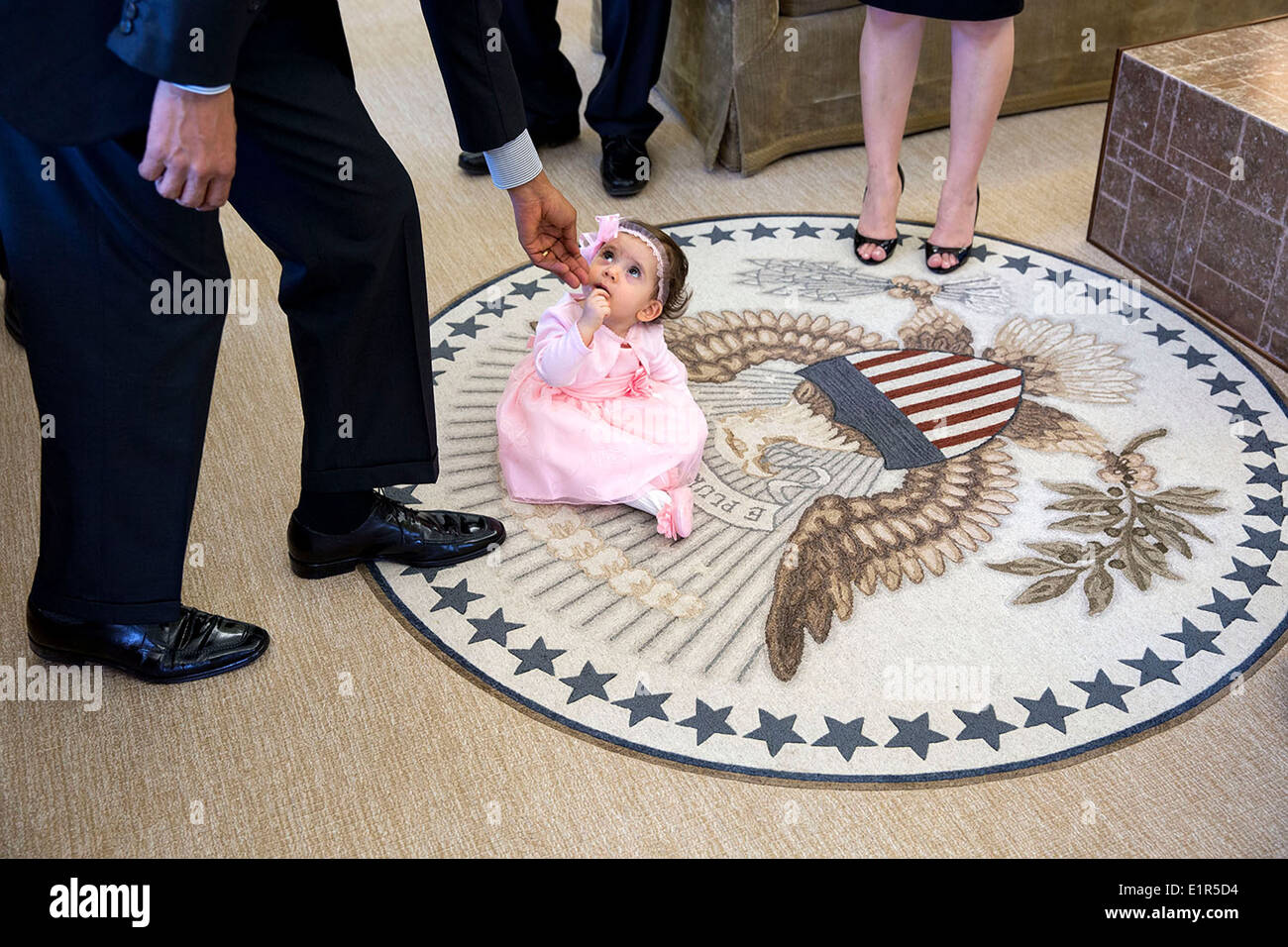 Le président américain Barack Obama atteint jusqu'à 6 mois, Sabina Johnson assis sur le sceau présidentiel lors d'une visite au bureau ovale avec son oncle, Elbek, Elibaev pour son Make-A-Wish visite à la Maison Blanche le 11 avril 2014 à Washington, DC. Banque D'Images