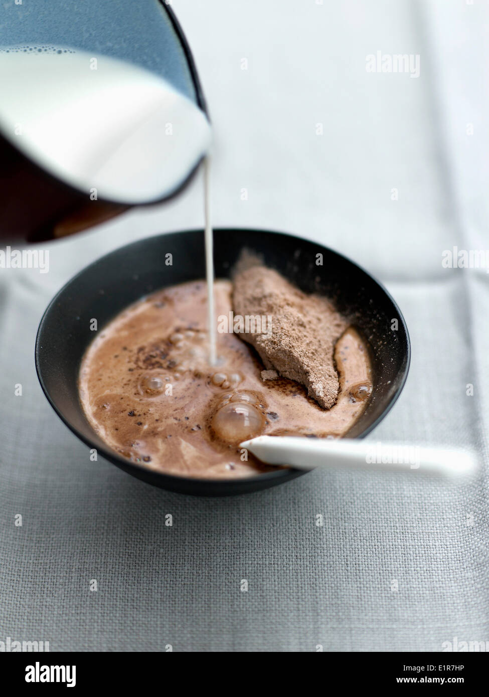 Verser le lait chaud sur le cacao et sucre Banque D'Images