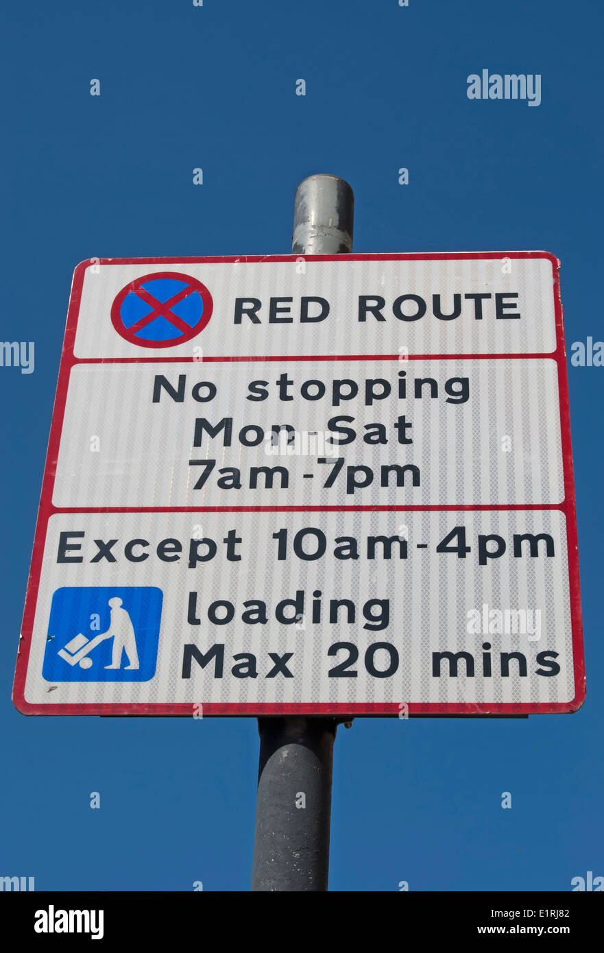 British Red route road sign donnant fois lorsqu'aucun arrêt n'est autorisé, sauf pour le chargement à certains moments Banque D'Images