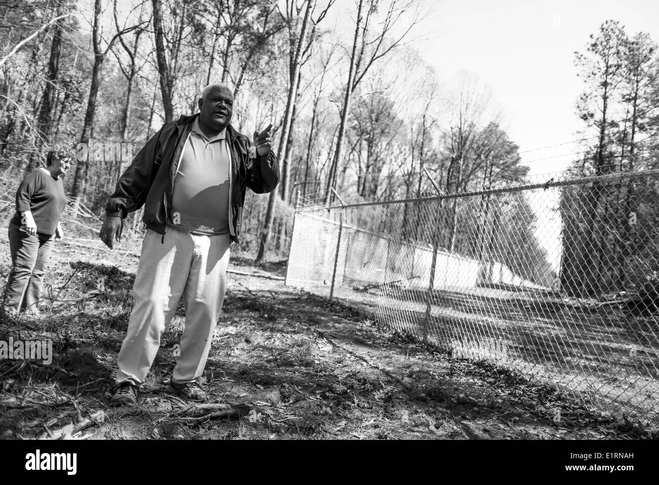 Crossett, Arkansas, USA. Mar 15, 2013. Ouachita Riverkeeper Cheryl Slavant et le pasteur David Bouie à pied sur sa propriété par la barrière qui marque Georgia-Pacific dans propriété Crossett, Arkansas. Des 15 maisons dans les environs 12 personnes sont décédées d'un cancer à un taux au-dessus de la moyenne nationale. De nombreux résidents locaux croient que le décès et maladies sont le résultat de la pollution causée par l'usine de contreplaqué de Georgia-Pacific et papier qui est administré par les frères Koch. © Nicolas Czarnecki/ZUMAPRESS.com/Alamy Live News Banque D'Images