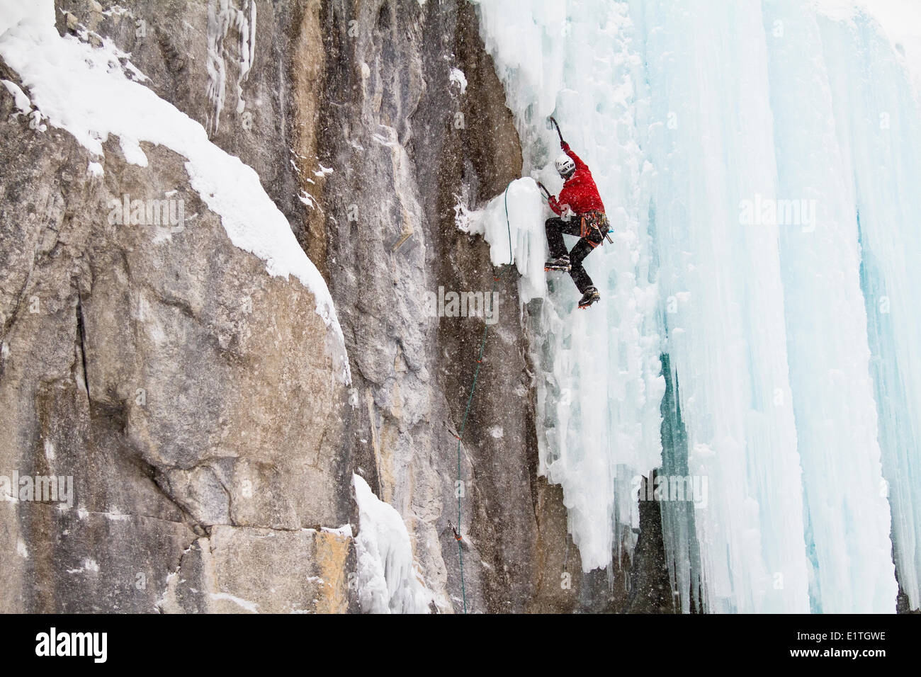 Jeune homme grimpe dans un mélange de glace et de roche tandis que l'escalade sur glace dans le parc national de Banff, près de Banff, Alberta, Canada. Banque D'Images