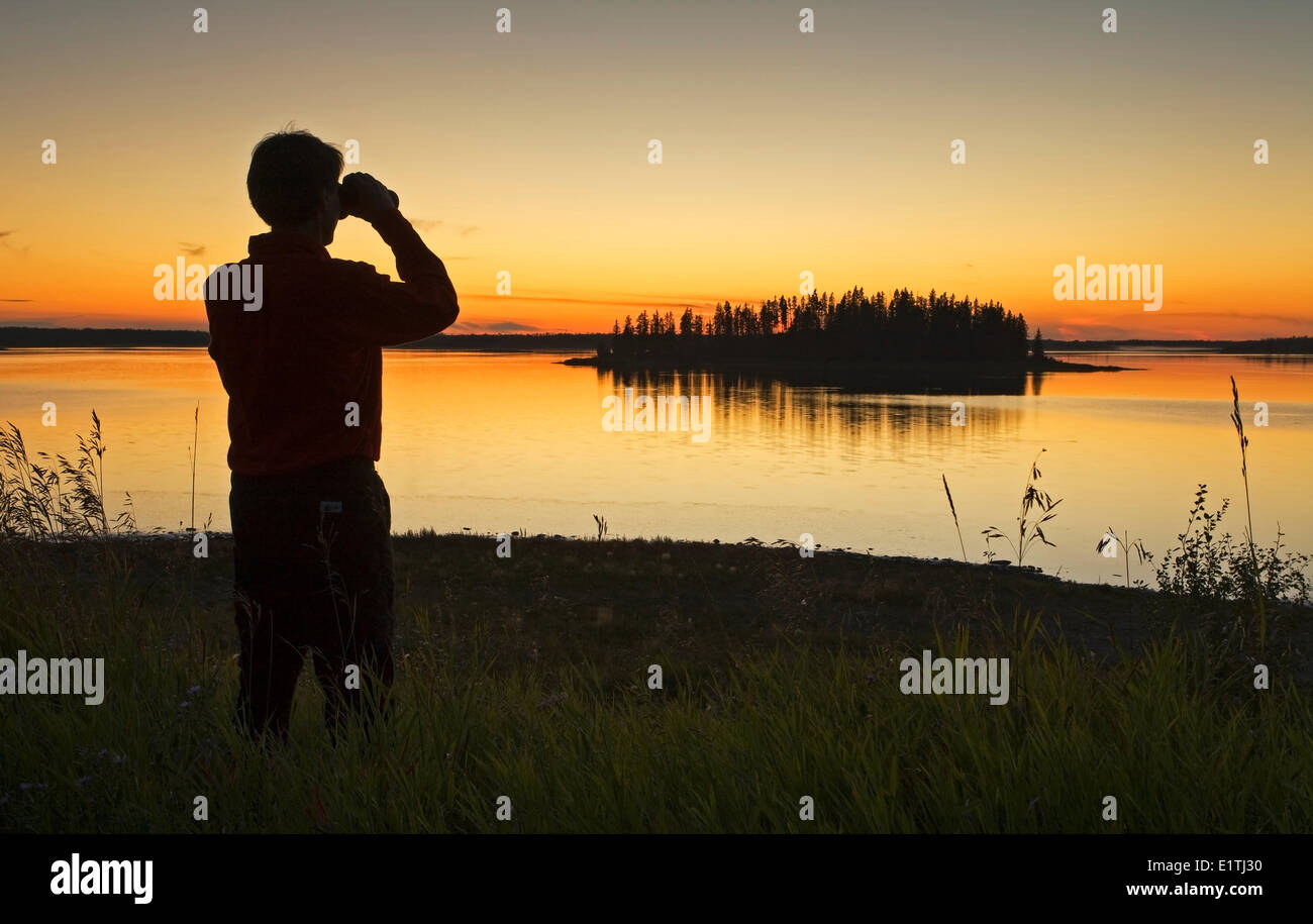 L'âge moyen male hiker surplombant le lac Astotin avec les jumelles au crépuscule, Elk Island Park, Alberta, Canada. Banque D'Images