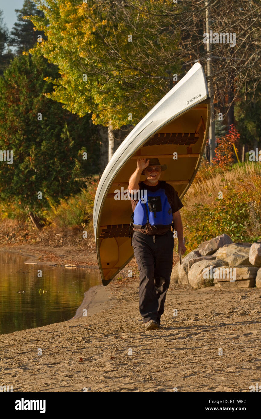 Homme mature porte canoe à partir de l'eau, lac Oxtongue, Muskoka, Ontario, Canada. Banque D'Images