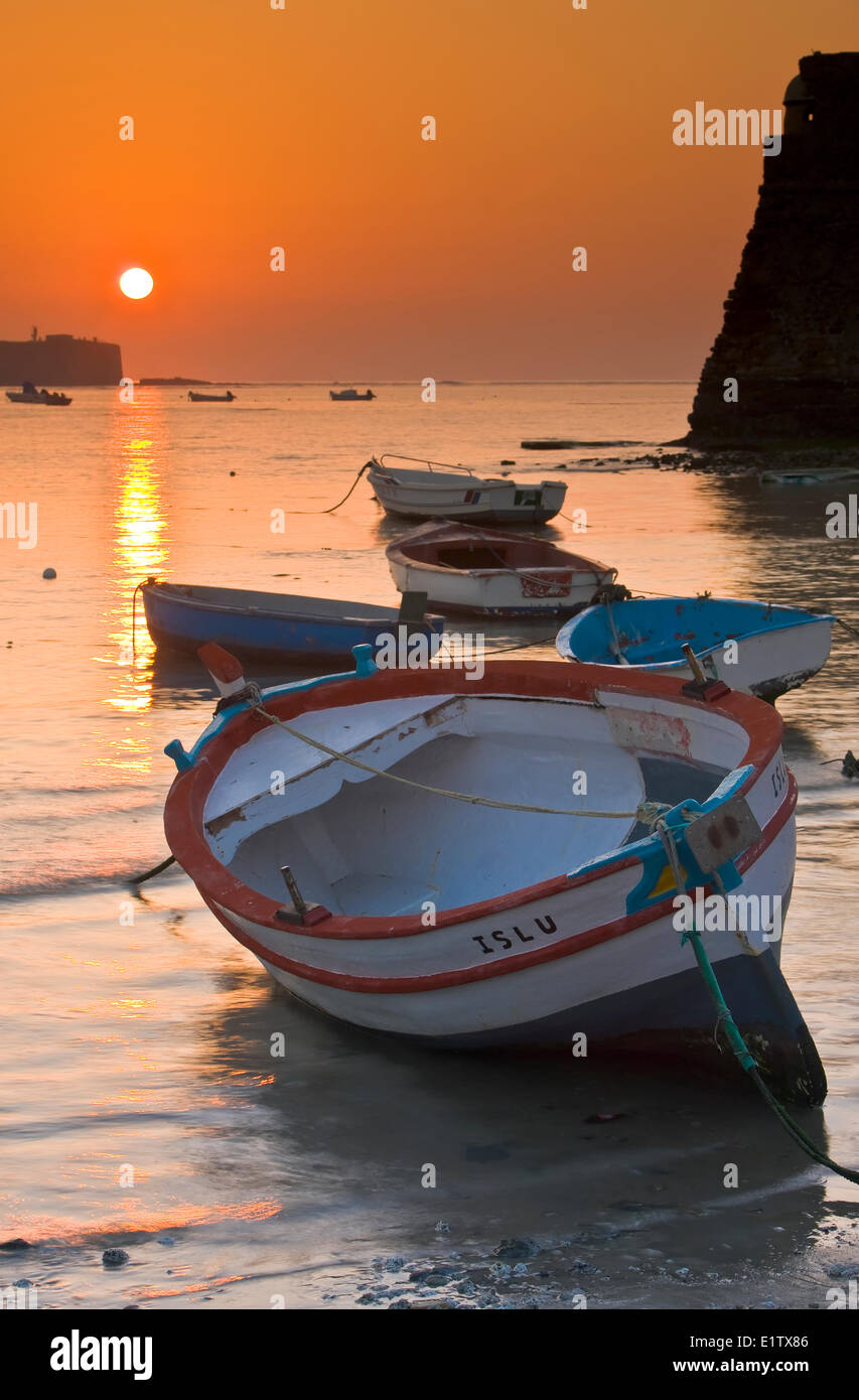 Petits bateaux de pêche ancrés à Playa de la Caleta au coucher du soleil dans la ville de Cadix, Province de Cadiz, Costa de la Luz, Andalousie Banque D'Images