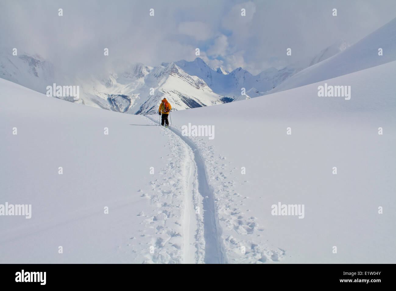 Un skieur d'arrière-pays ski retour à la lodge après une journée ensoleillée dans les Rocheuses canadiennes. Cascade Lodge, Golden, BC Banque D'Images