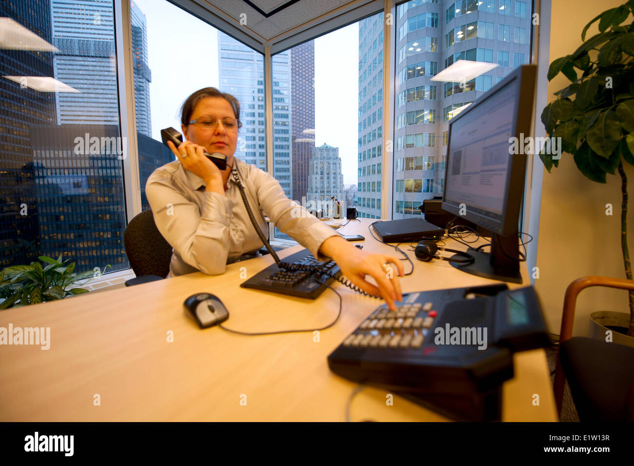 Femme d'affaires exécutif dans un bureau du coin assis au bureau à parler au téléphone, à Toronto (Ontario) Banque D'Images