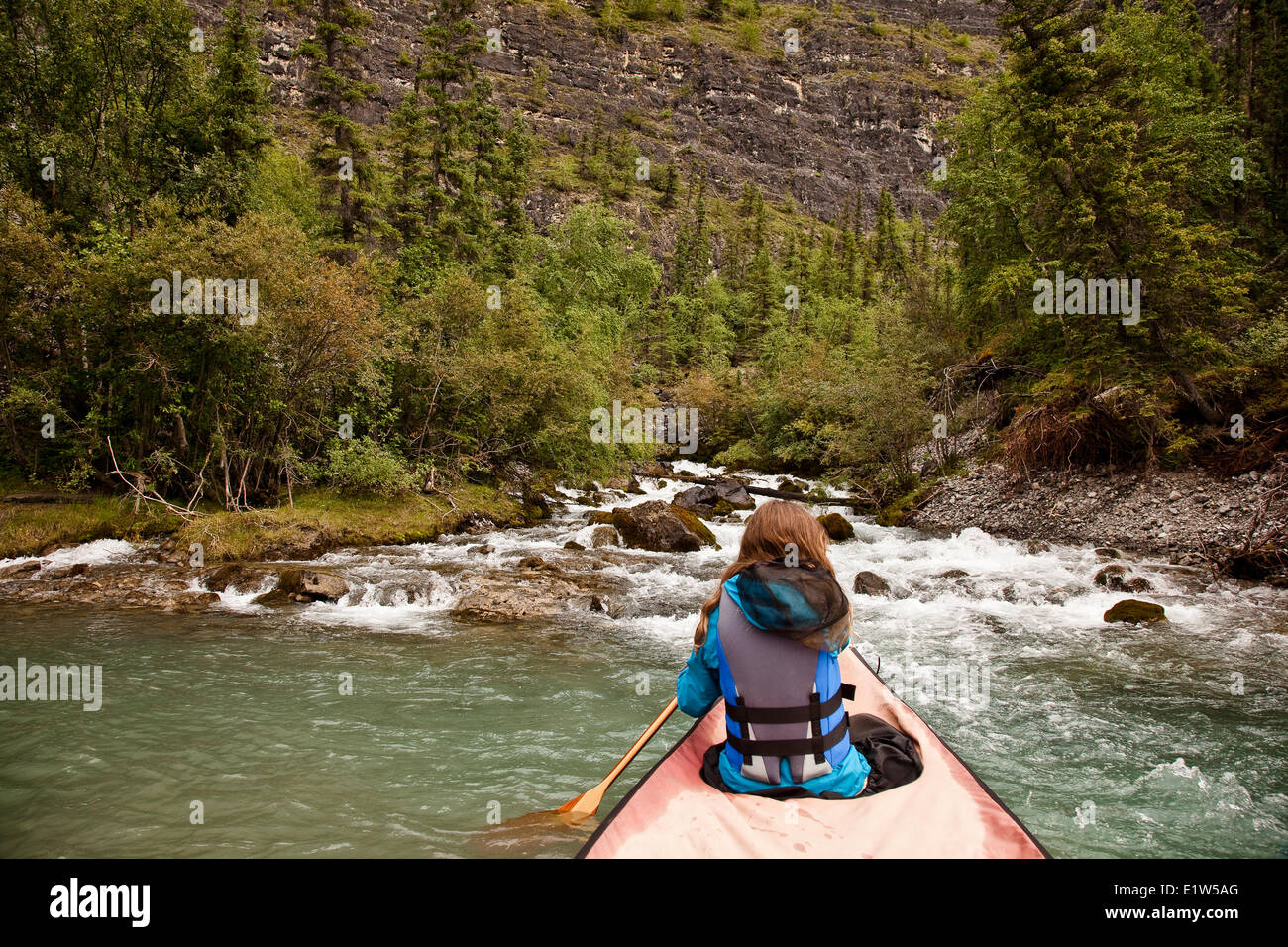 Jeune fille en canoe approches Livre blanc de printemps de pulvérisation sur la rivière Nahanni, la réserve de parc national Nahanni, Territoires du Nord-Ouest, préserver le Canada. Banque D'Images