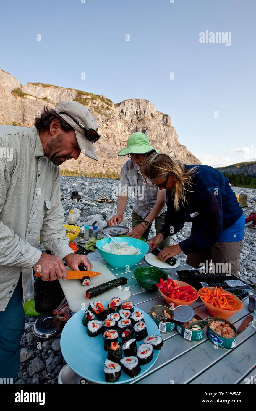 Trois adultes préparer sushi alors que le campement sur les rivière Nahanni, la réserve de parc national Nahanni, Territoires du Nord-Ouest, préserver le Canada. Banque D'Images