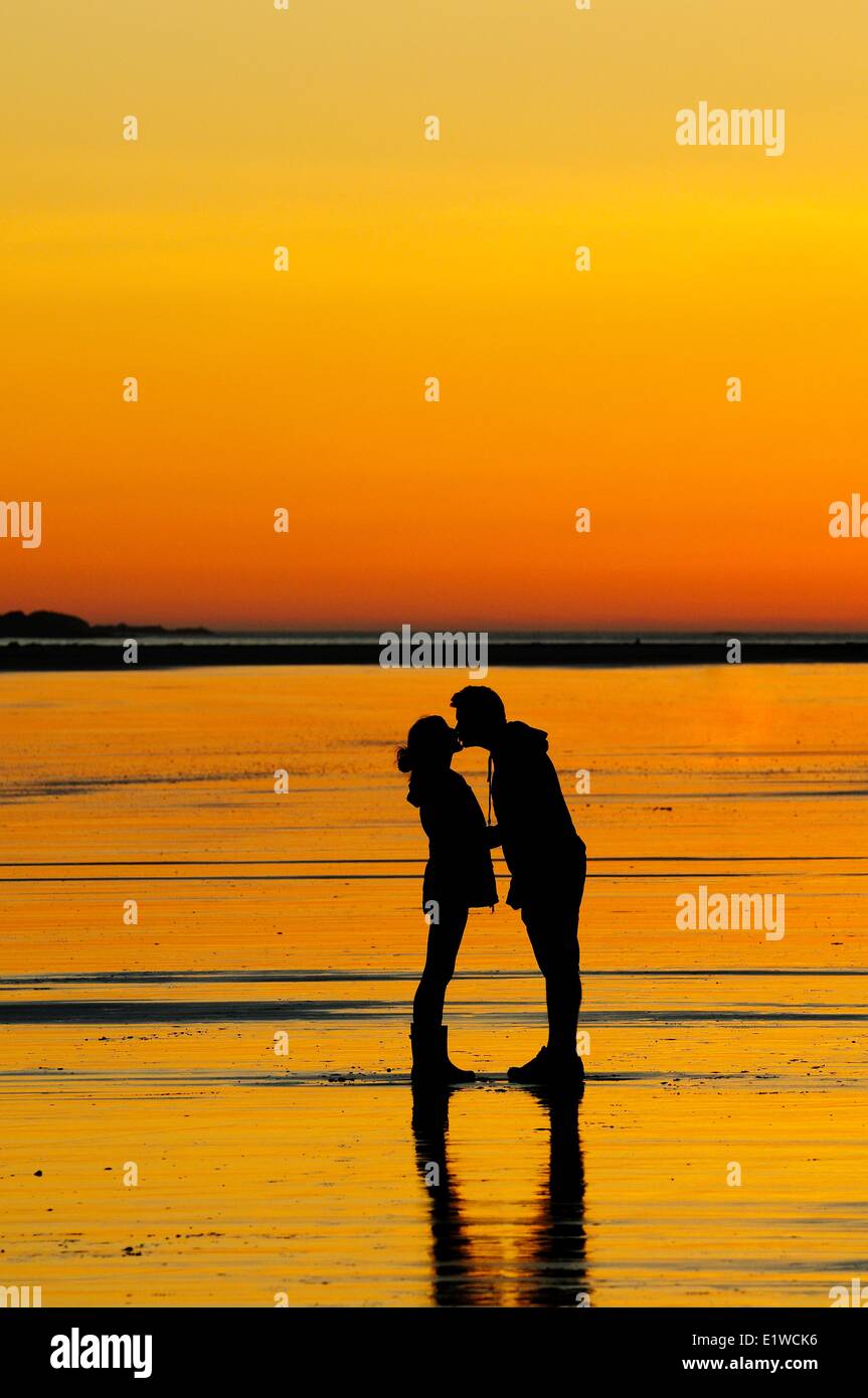 Un jeune couple au coucher du soleil sur le point de baiser tandis que sur Chesterman Beach près de Tofino, en Colombie-Britannique. Banque D'Images