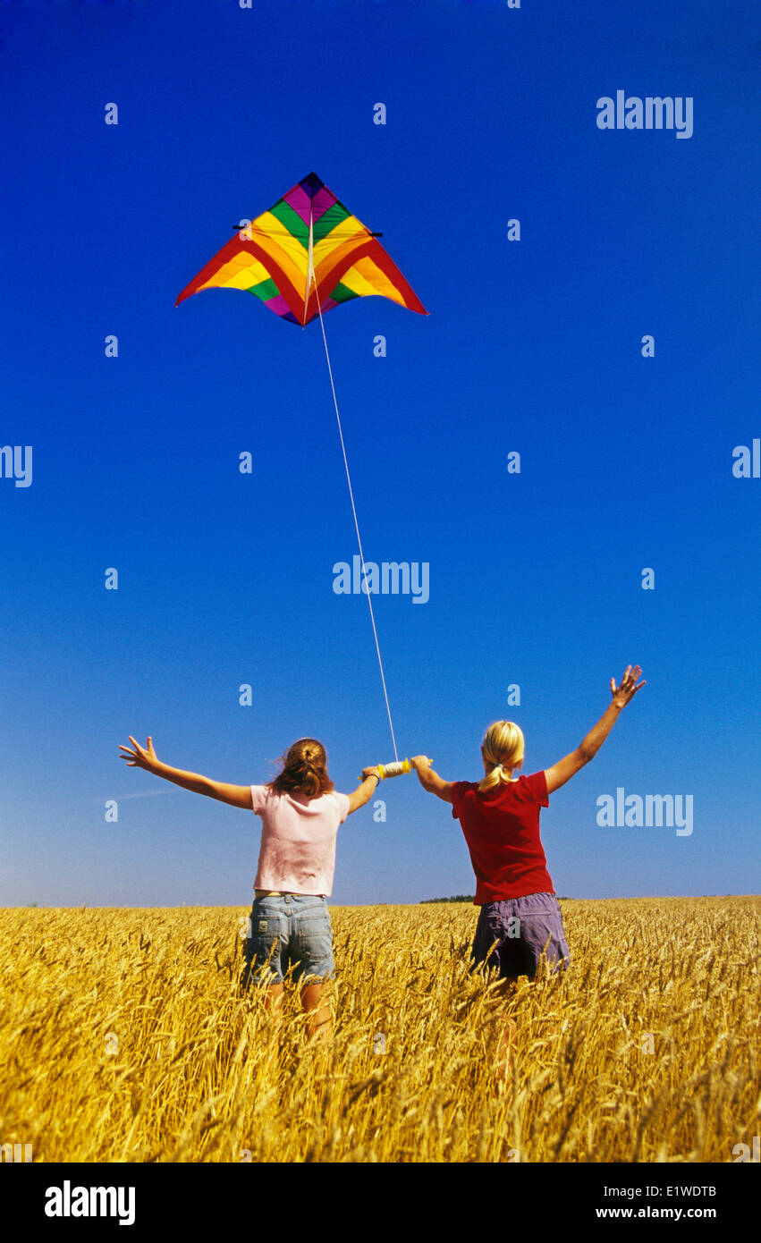 Deux filles dans un champ de blé de printemps flying a kite près de Winnipeg, Manitoba, Canada Banque D'Images