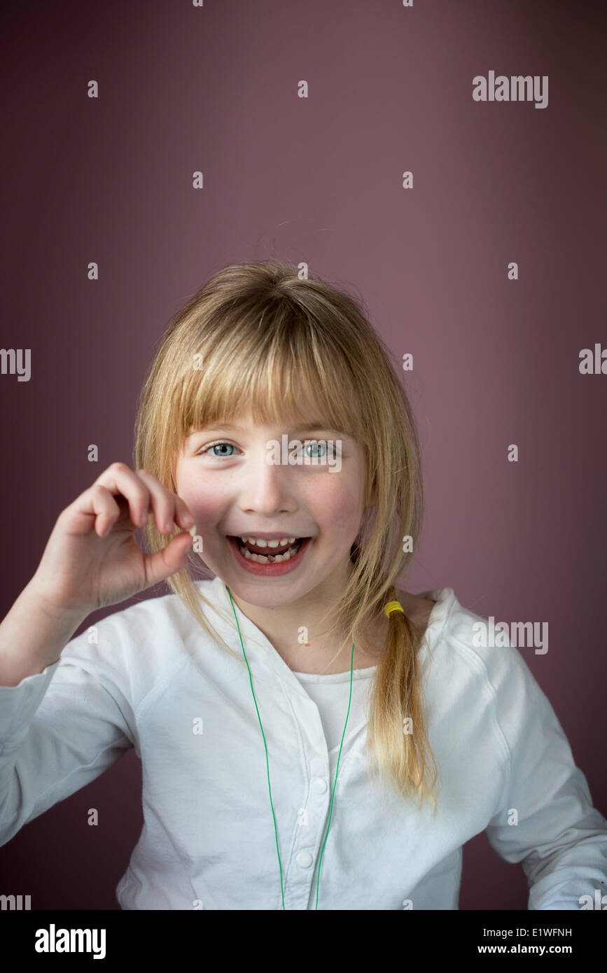 Smiling little girl montrant sa première dent lâche Banque D'Images