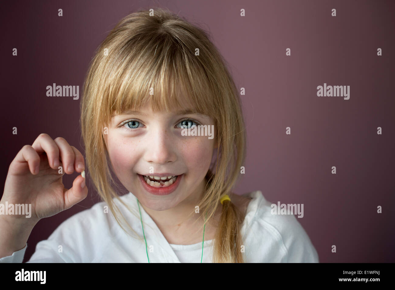 Portrait of smiling little girl montrant sa première dent lâche Banque D'Images