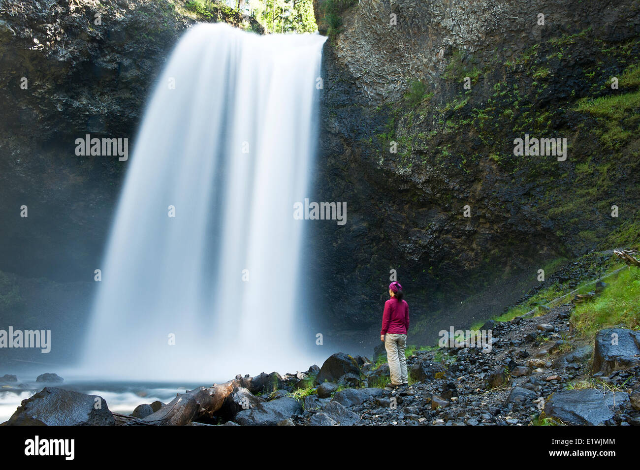 Une femme se trouve à côté de Moul Falls dans le parc provincial Wells Gray, C.-B.). Communiqué de modèle signé. Banque D'Images