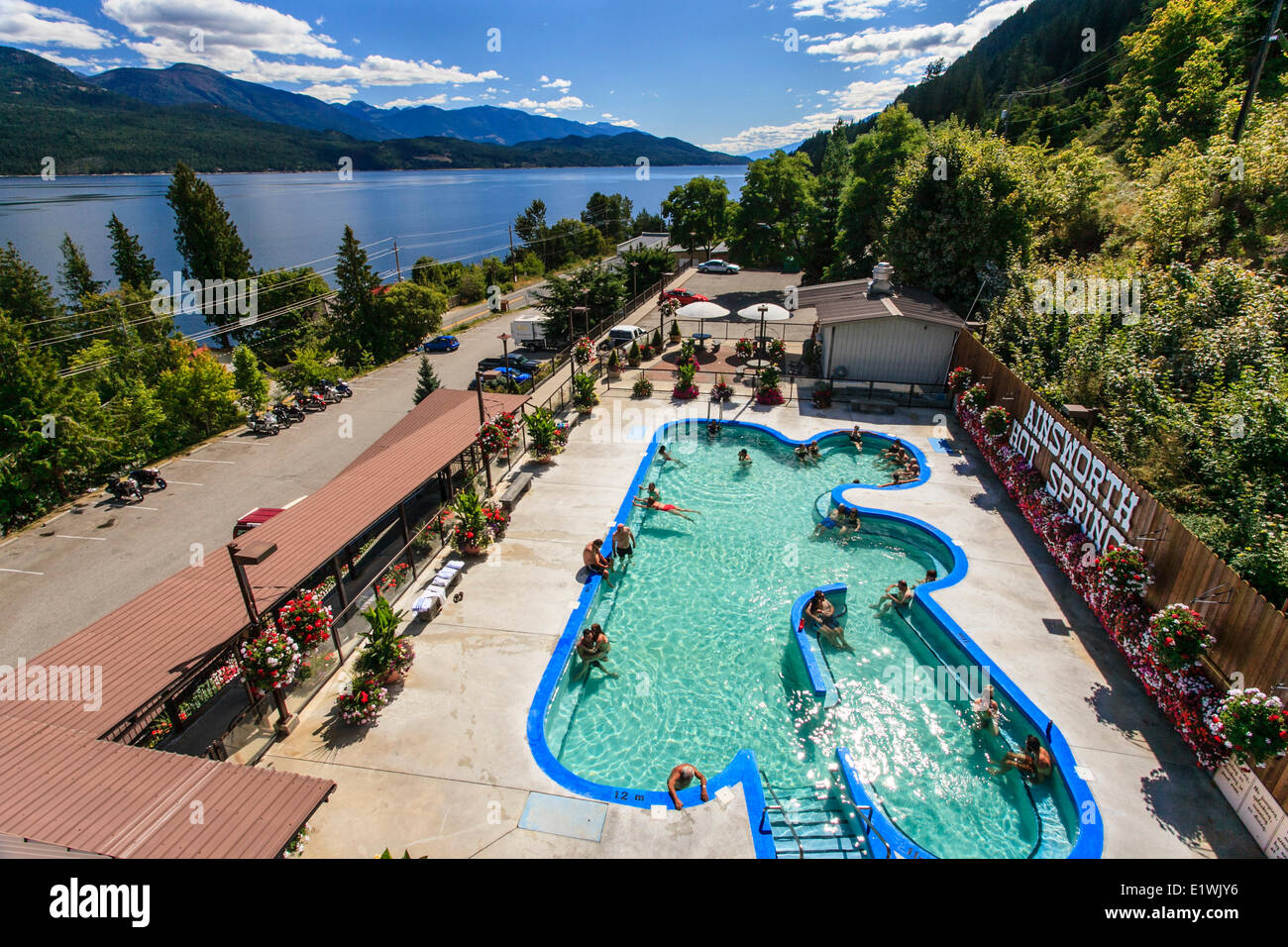 Salon des gens dans la piscine à Ainsworth Hot Springs Resort, avec le lac Kootenay à l'arrière-plan. Banque D'Images