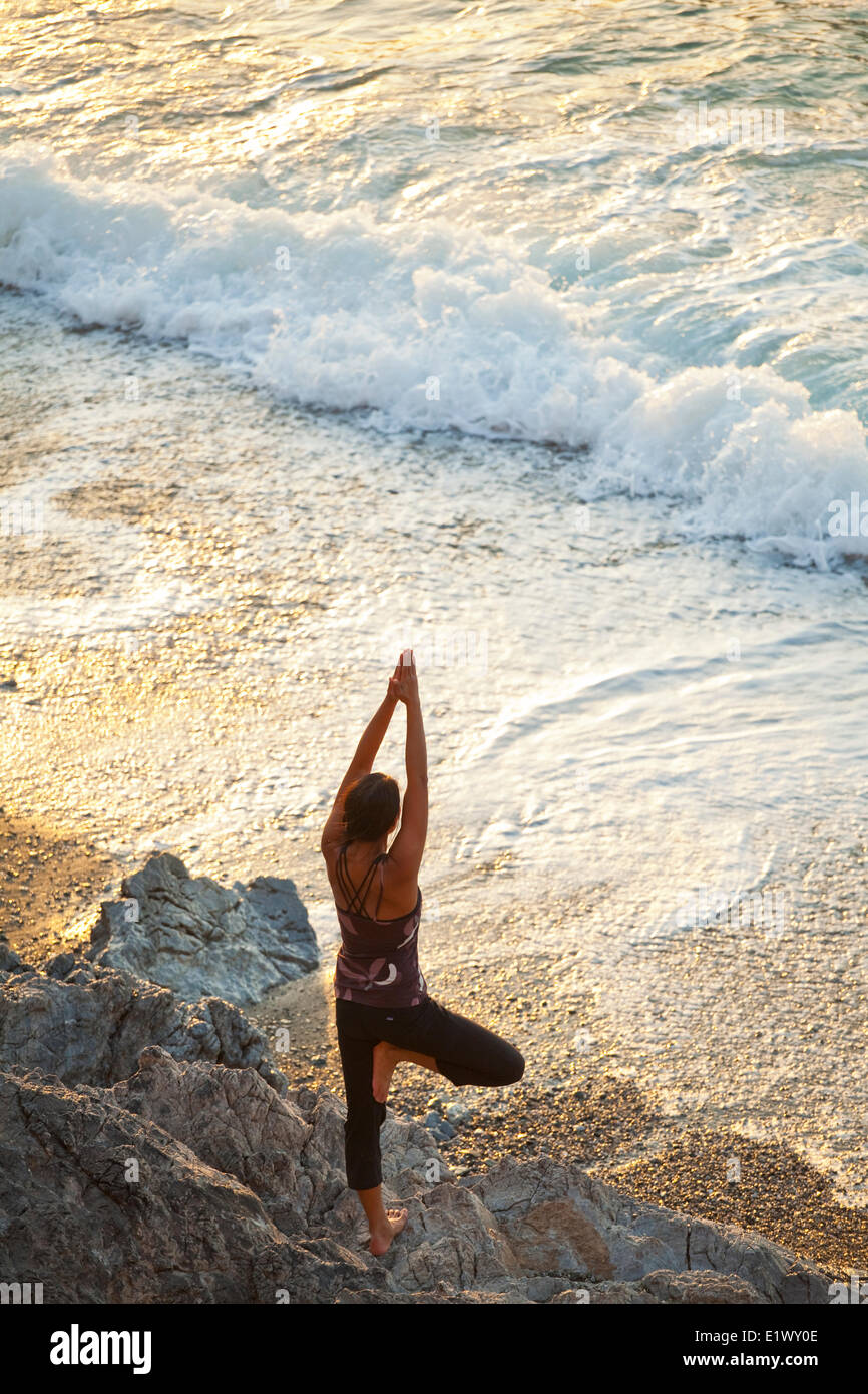 Une jeune femme faisant du yoga au coucher du soleil près de la plage à Kalymnos, Grèce Banque D'Images