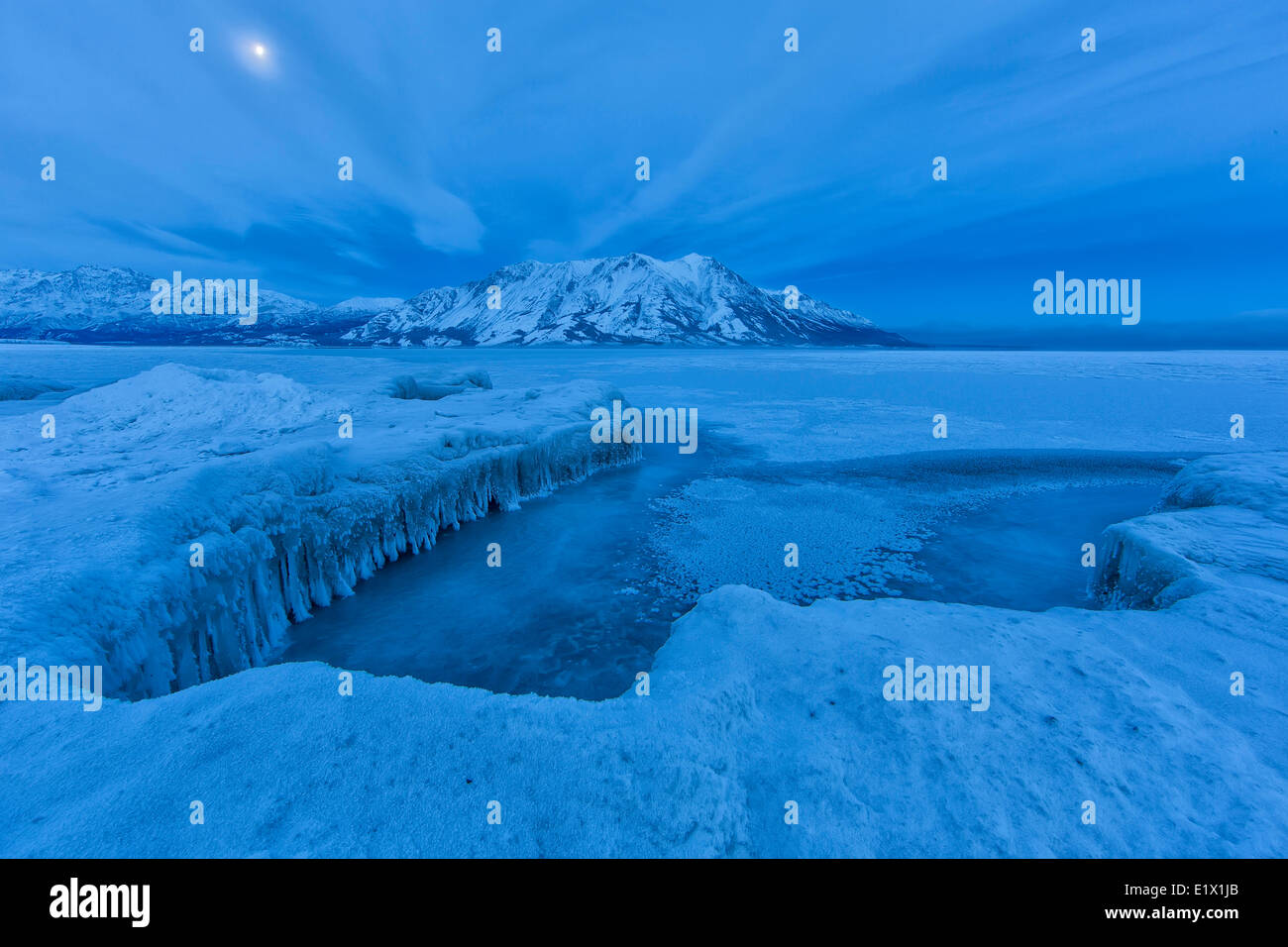 Après que la glace du lac Kluane a couvert partiellement le lac. La lune est visible sur le mont Sheep dans les premières heures du matin. Banque D'Images