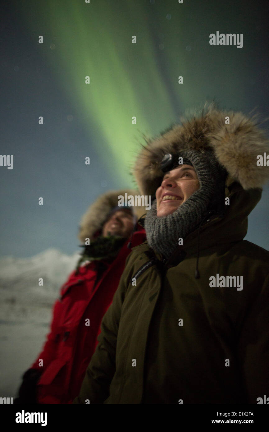 Les gens sourire en regardant les aurores boréales danser dans le ciel nocturne au-dessus d'eux, au Yukon. Banque D'Images