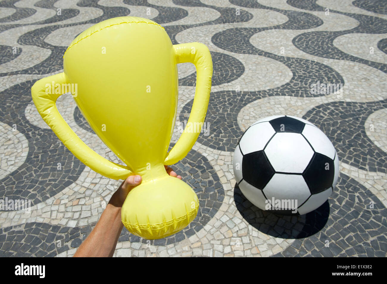Hand holding trophy ballon de soccer de football ci-dessus assis sur le trottoir à Copacabana Rio de Janeiro Brésil Banque D'Images