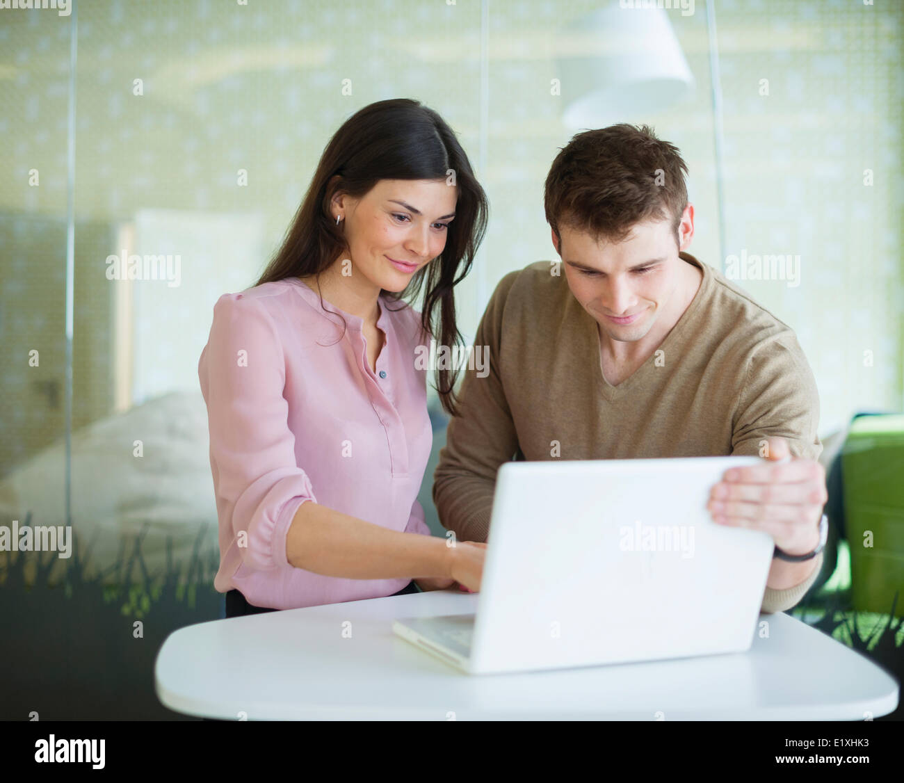 Young businessman and businesswoman using laptop at table Banque D'Images
