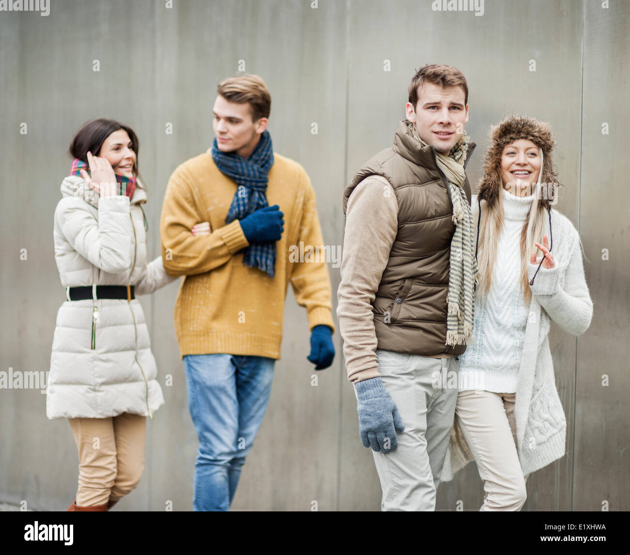 Smiling young couples walking against wall Banque D'Images
