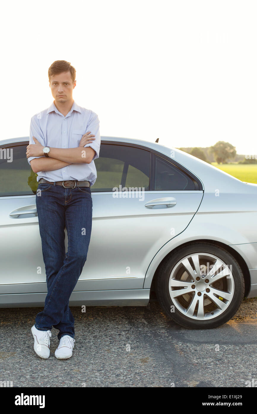 Portrait de jeune homme debout par voiture à la campagne Banque D'Images