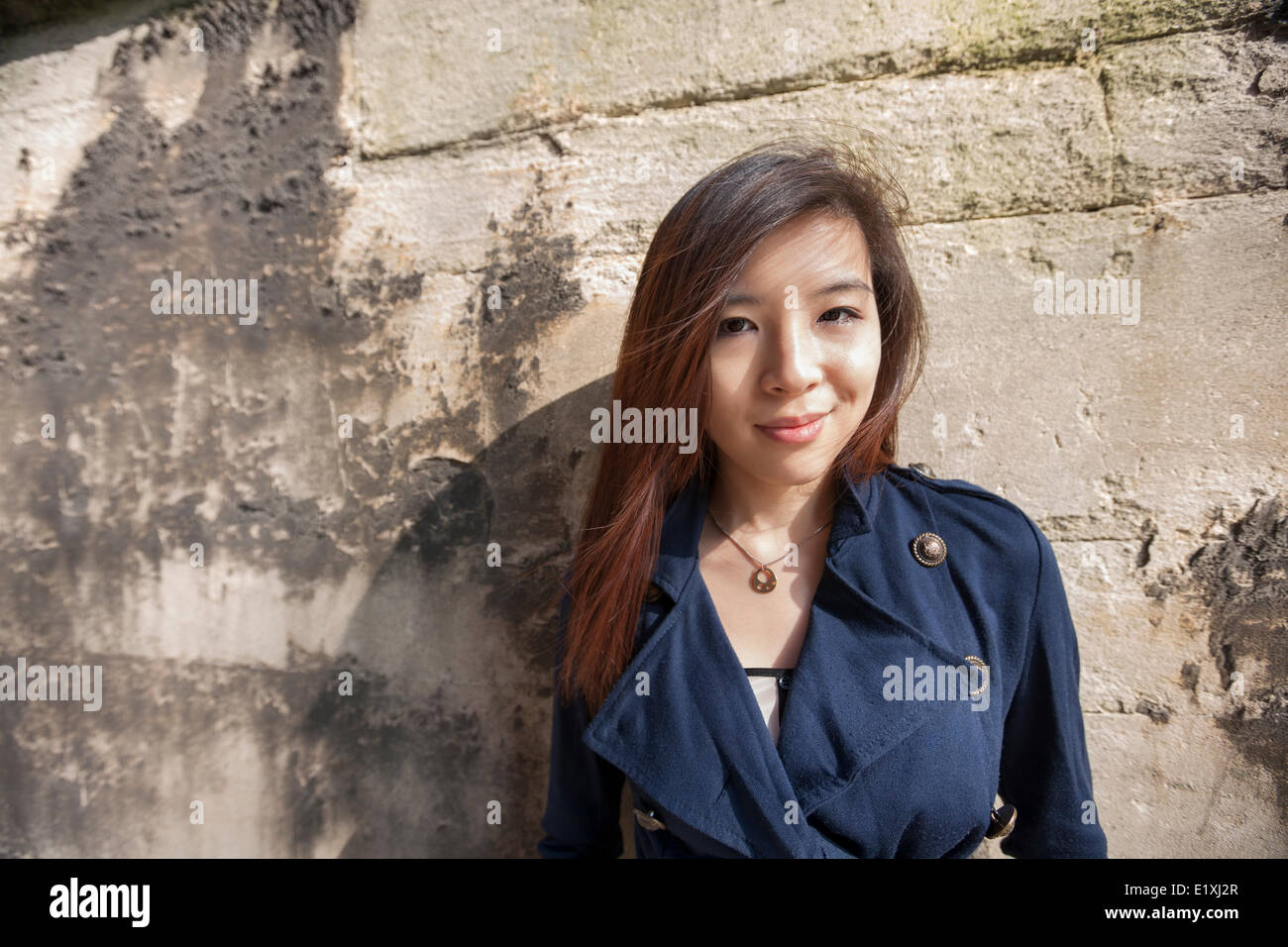 Portrait of Beautiful woman smiling tout en s'appuyant sur mur à Londres, Angleterre, Royaume-Uni Banque D'Images