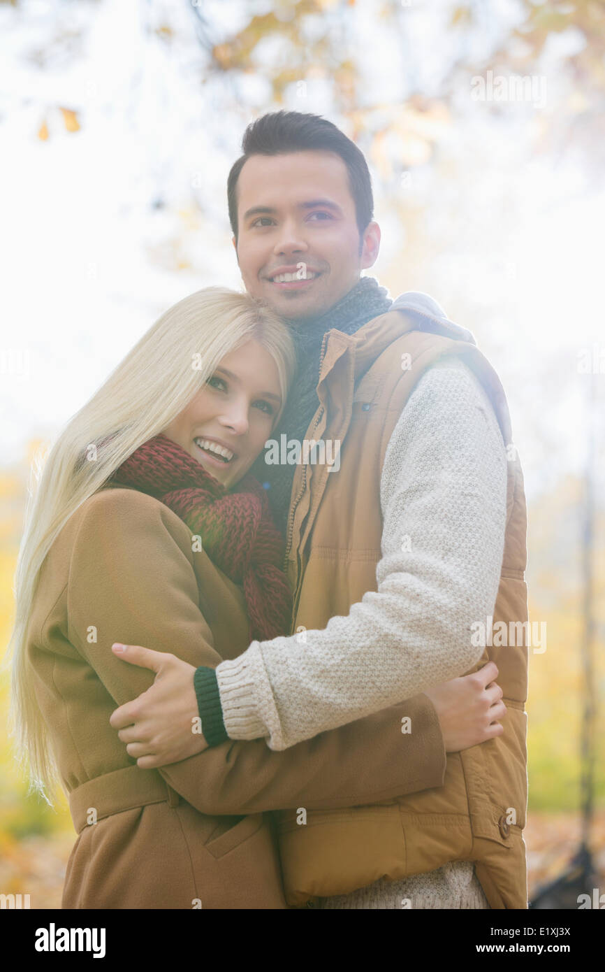 Heureux couple hugging in vestes en park Banque D'Images