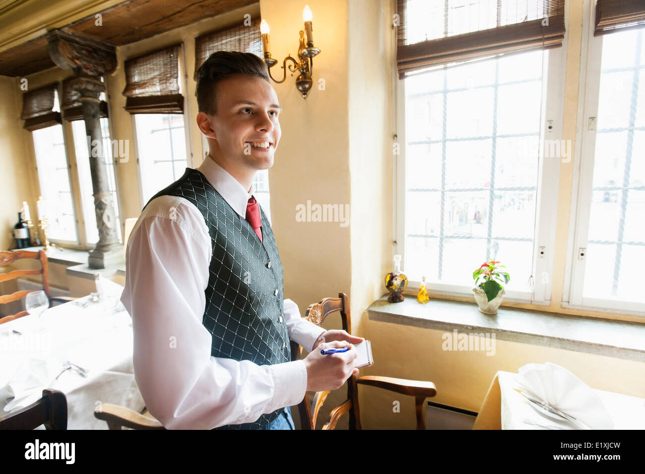 Vue de côté de serveur avec le bloc-notes smiling in restaurant Photo Stock  - Alamy