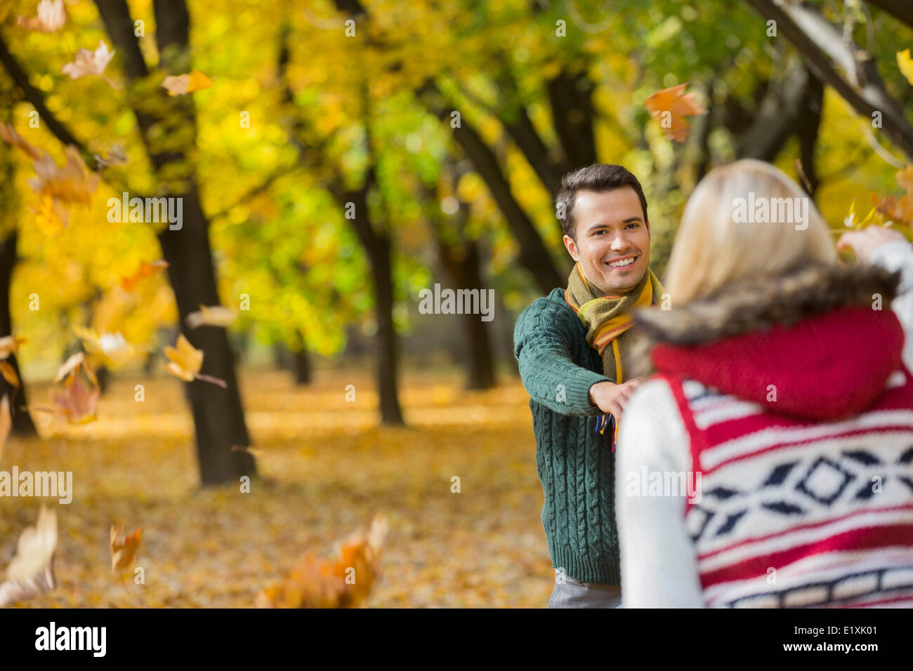 Couple heureux de jouer avec les feuilles d'automne dans le parc Banque D'Images